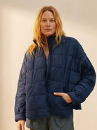 woman wearing navy blue lightweight puffer travel jacket with front zipper and pockets