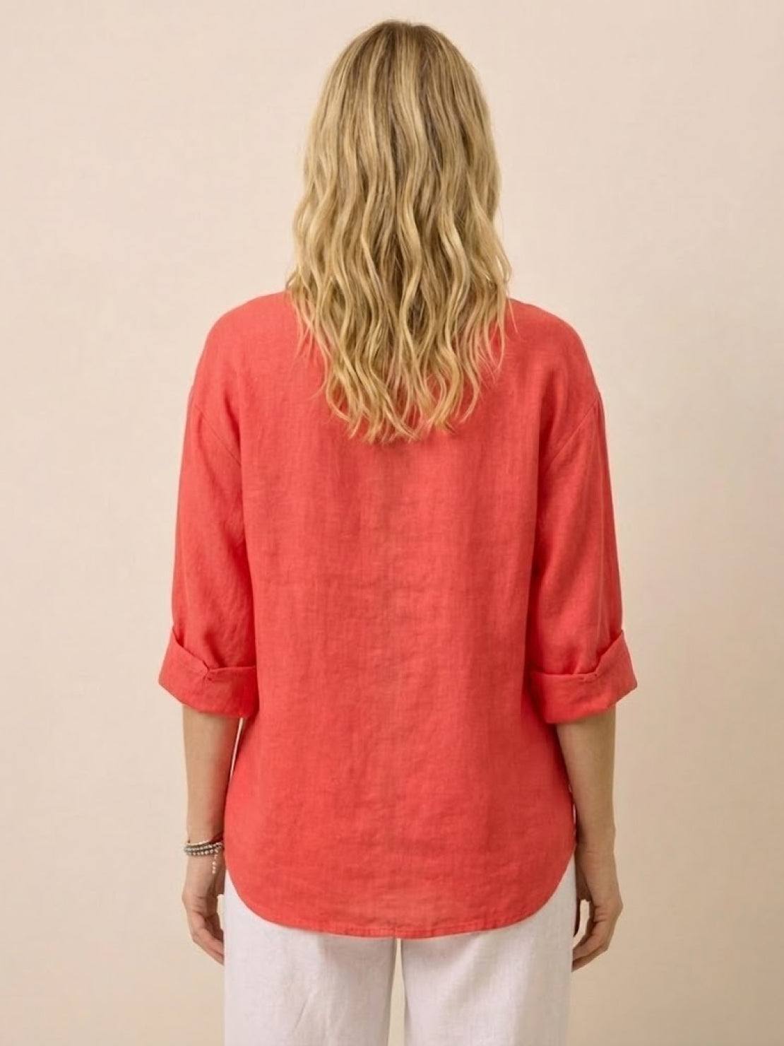 Back view of woman wearing coral Pure Linen Age-Defying Shirt with rolled sleeves and white pants