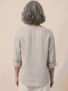 white pure linen age-defying shirt with button details hanging on wooden hanger
