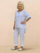 woman wearing white asymmetrical two-piece trouser set with rolled sleeves and tapered pants