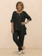 Woman wearing black asymmetrical two-piece trouser set with rolled sleeves and tapered pants