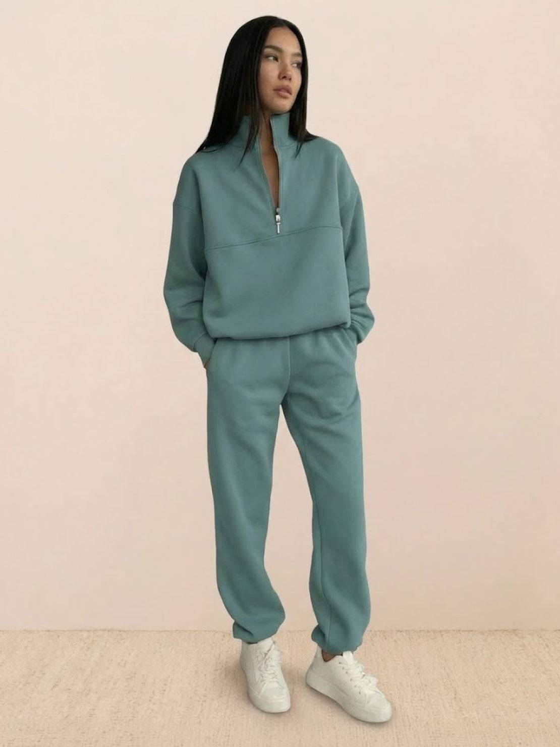 Woman wearing a cotton-blended two-piece tracksuit with high collar and deep zipper, styled for casual comfort and confident athleisure look
