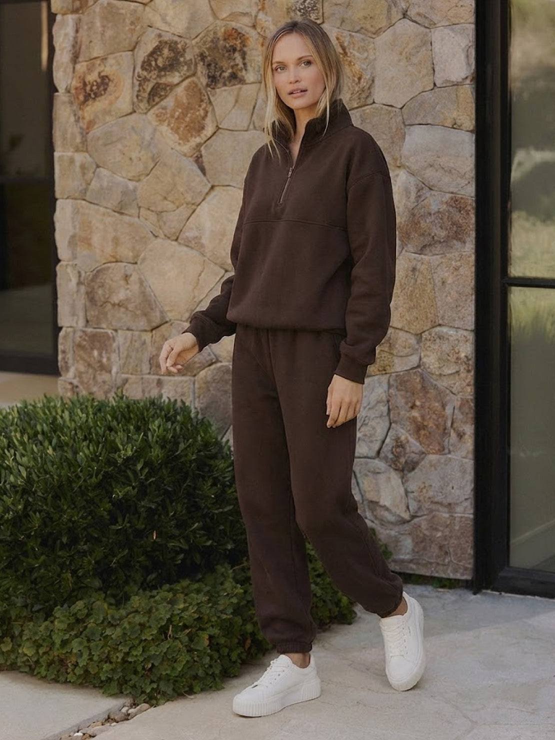Woman wearing a stylish cotton-blended two-piece tracksuit with high collar and deep zipper, showcasing casual comfort and polished athleisure style.
