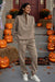 Woman wearing beige Classic Airplane Set tracksuit standing among Halloween pumpkins on front porch