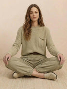 Woman wearing European minimalism relaxed khaki knit sweater and trouser set sitting cross-legged
