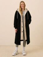 Woman wearing black cozy sherpa lined everyday wear oversized long coat with hood and casual outfit