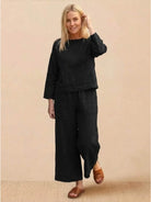 Woman wearing loose solid color black two-piece set with wide-leg pants and long-sleeve top