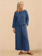 Woman wearing loose solid color blue two-piece set with long sleeves and wide-leg pants