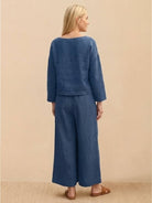 Loose solid color blue two-piece set with loose fit top and wide-leg pants on a woman standing against beige background