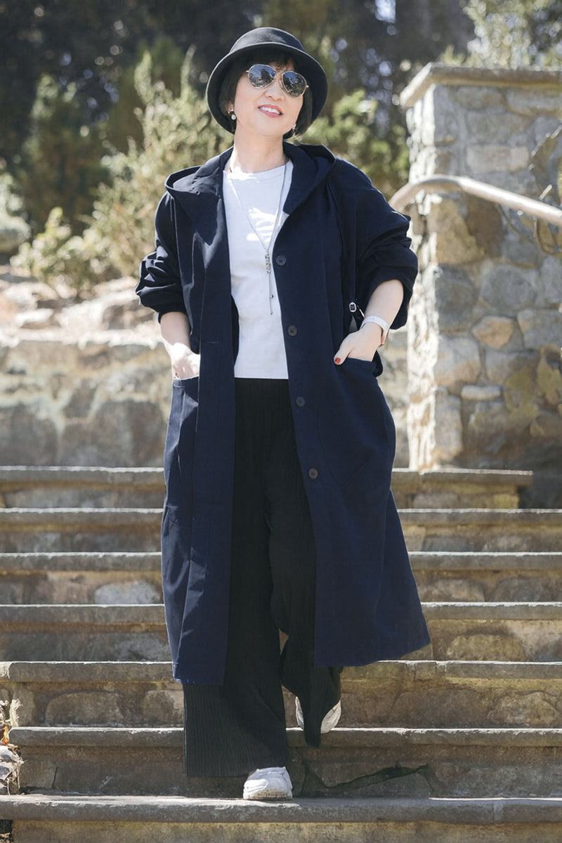 Woman wearing oversized navy Heritage Windbreaker Jacket with hood and snap buttons on outdoor stairs