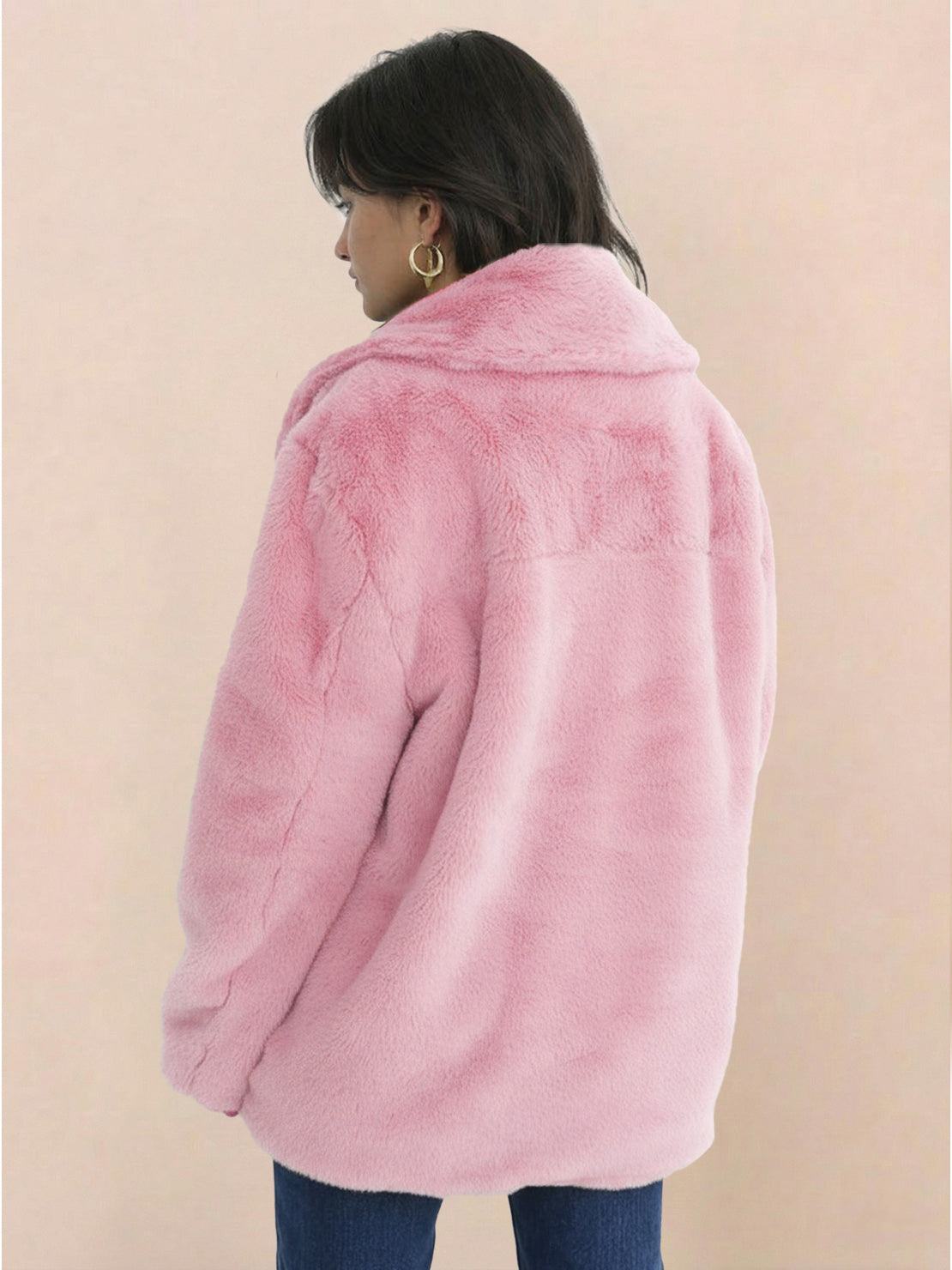 Back view of a woman wearing a soft pink open front oversized faux fur jacket with draped shawl collar and mid-hip length.