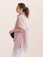 Oversized linen shirt in white with relaxed fit and back button detail displayed on hanger