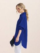 Oversized linen shirt hanging on a white background showing relaxed fit and back button details