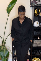 Black oversized linen shirt with relaxed fit and long sleeves worn by woman indoors