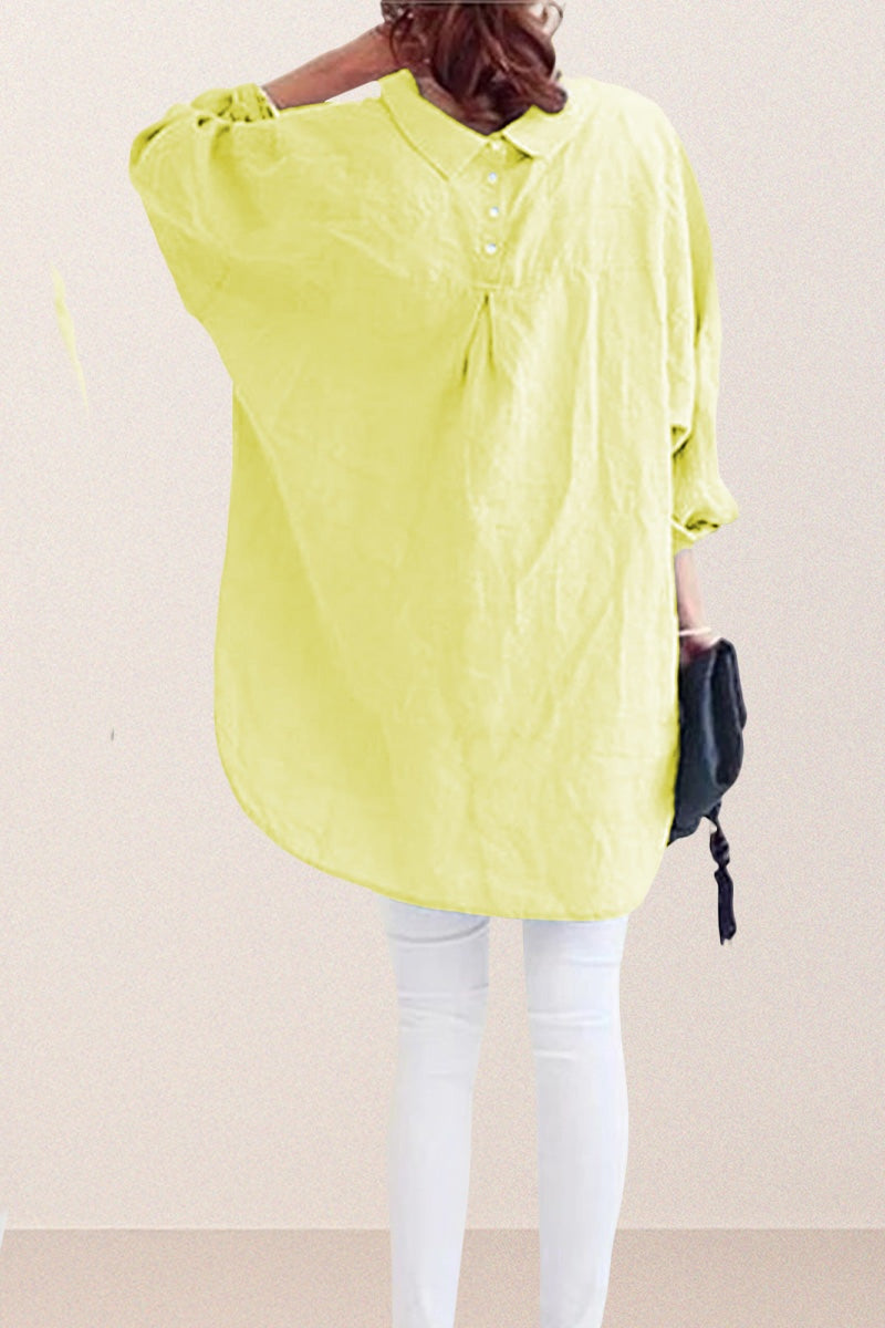 Back view of oversized linen shirt in soft yellow with button detail, worn with white pants and holding a black clutch.