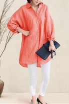 Woman wearing oversized linen shirt in sun-washed pink with white leggings and black heels holding a navy clutch bag