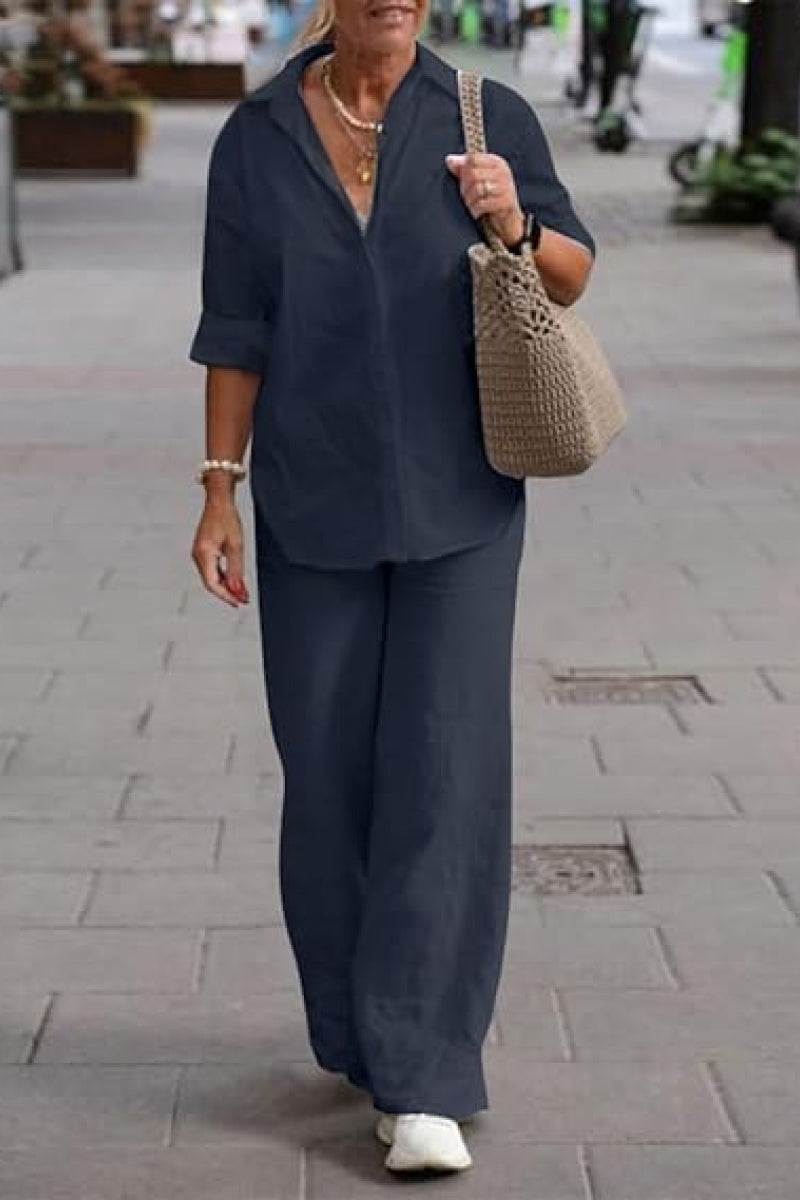 Woman wearing oversized 100% cotton navy shirt and wide-leg pants co-ord set walking outdoors with beige crochet tote bag and white sneakers.