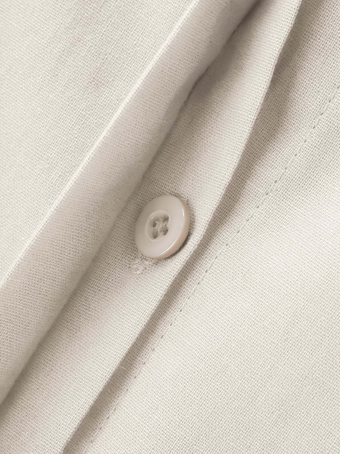 Close-up of oversized 100% cotton shirt fabric with button detail