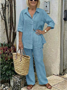 Woman wearing oversized 100 cotton shirt and wide-leg pants co-ord set in blue with rolled sleeves and straw tote bag