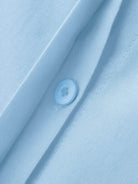Close-up of oversized 100% cotton shirt fabric and button in light blue color