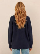 Woman wearing relaxed fit oversized navy knit cardigan from back view