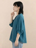 Relaxed loose breathable linen blouse in teal worn by woman with short hair and earrings