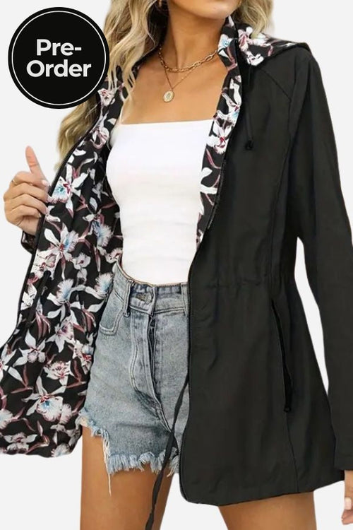 Reversible floral raincoat with solid black exterior and floral print interior, featuring a hood and drawstring waist for a feminine silhouette.