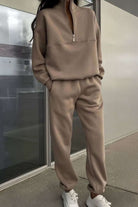 Neutral tone cotton blend tracksuit with zip neckline and stretch waistband, styled casually with white sneakers.