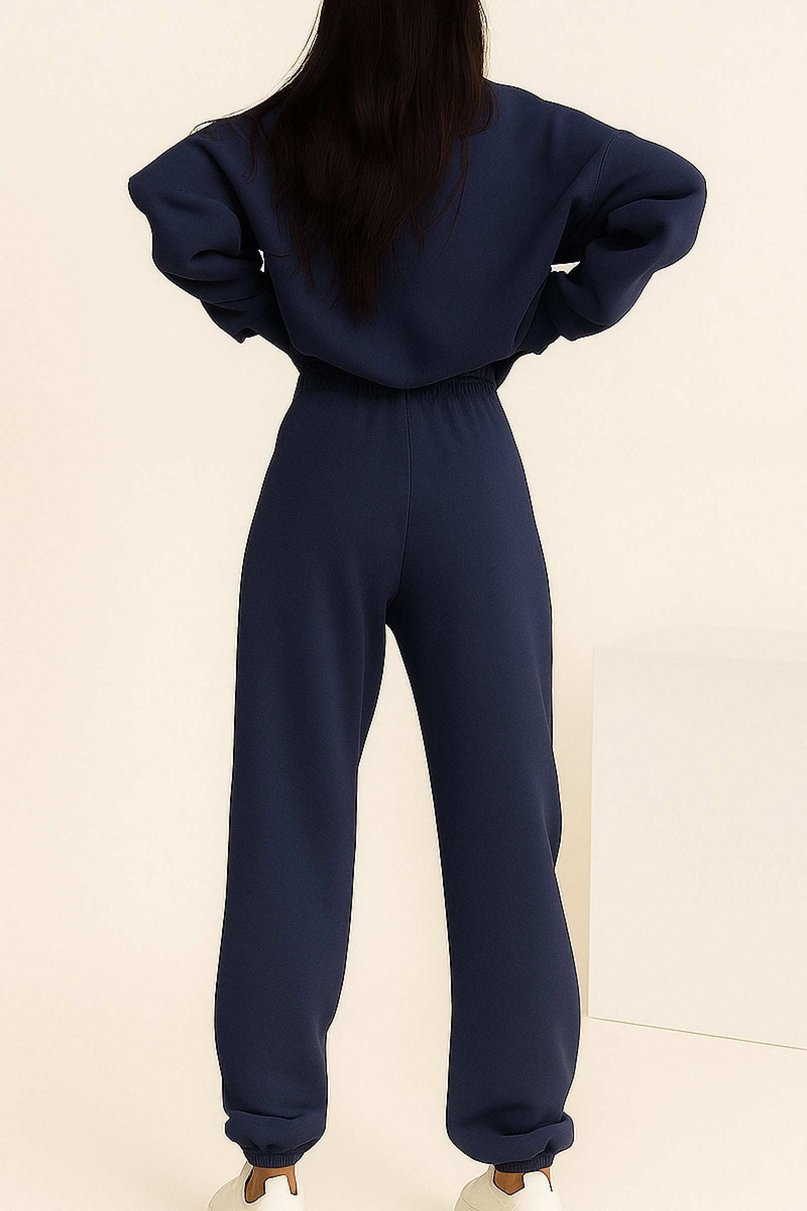 Woman wearing navy blue cotton blend tracksuit with long sleeves and elastic waist and cuffs, viewed from back.