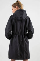 Back view of a woman wearing a black Rain Couture Windbreaker with an adjustable hood and oversized fit.