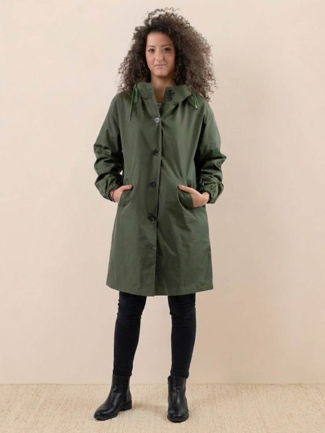 Woman wearing green oversized Rain Couture Windbreaker jacket with hood and pockets