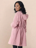 Woman wearing pink oversized Rain Couture Windbreaker jacket with adjustable hood and cinched waist.