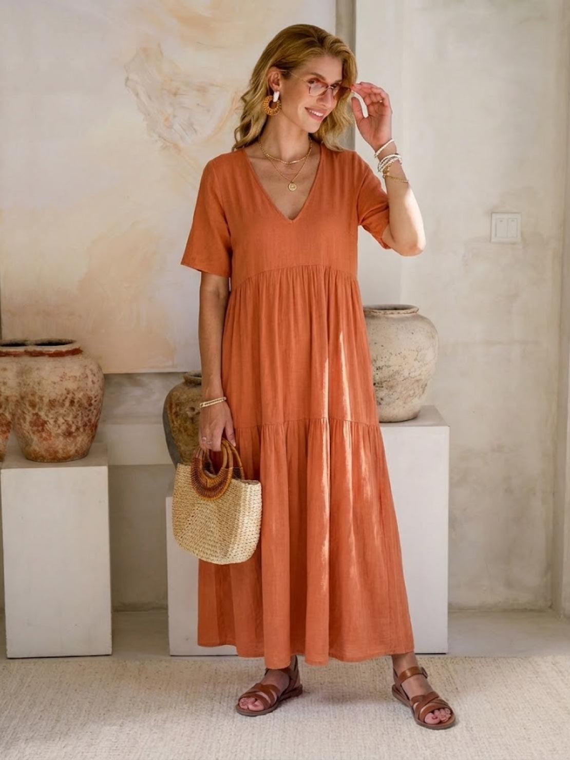 Woman wearing a V-neck two-tiered maxi swing dress in flowing cotton fabric with irregular hemline and loose sleeves