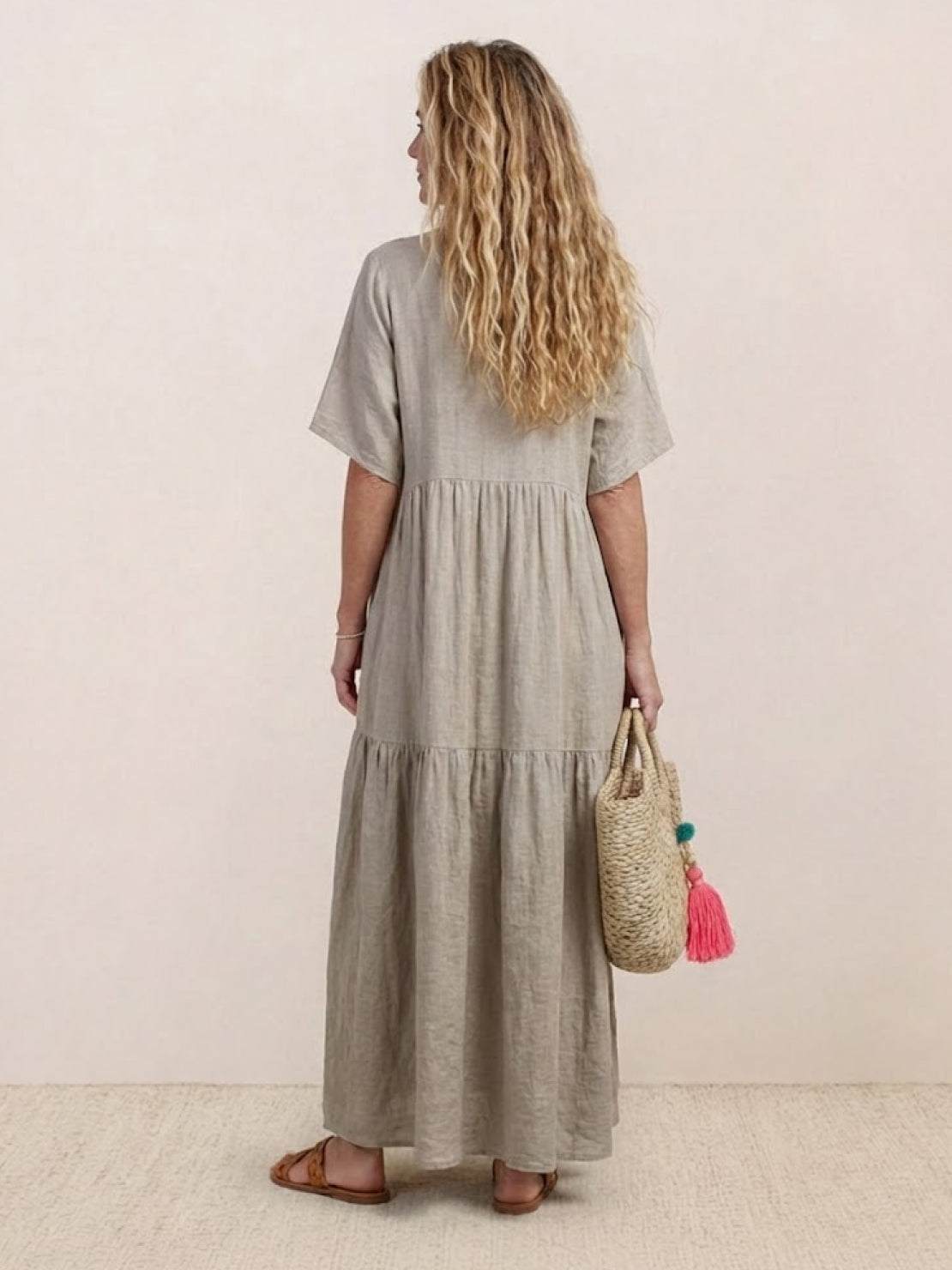 Women wearing V-neck two-tiered maxi swing dress in flowing cotton fabric with irregular hem and draped sleeves.
