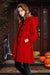 Woman wearing a red water-resistant oversized hooded windbreaker rain jacket standing by a Halloween-decorated front door with pumpkins.